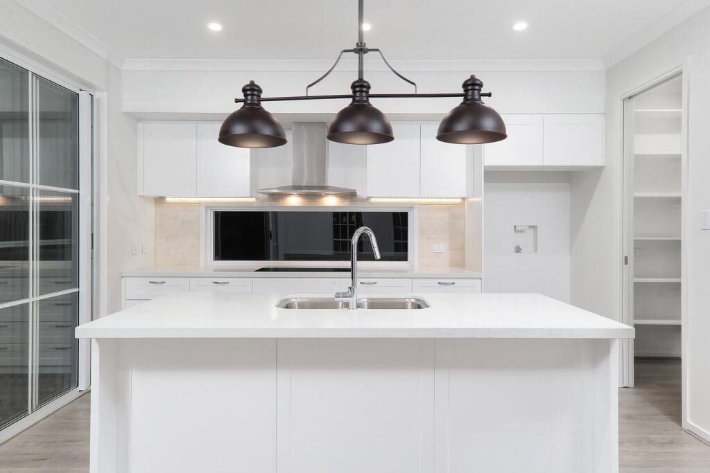 A white kitchen with an island and unique light feature