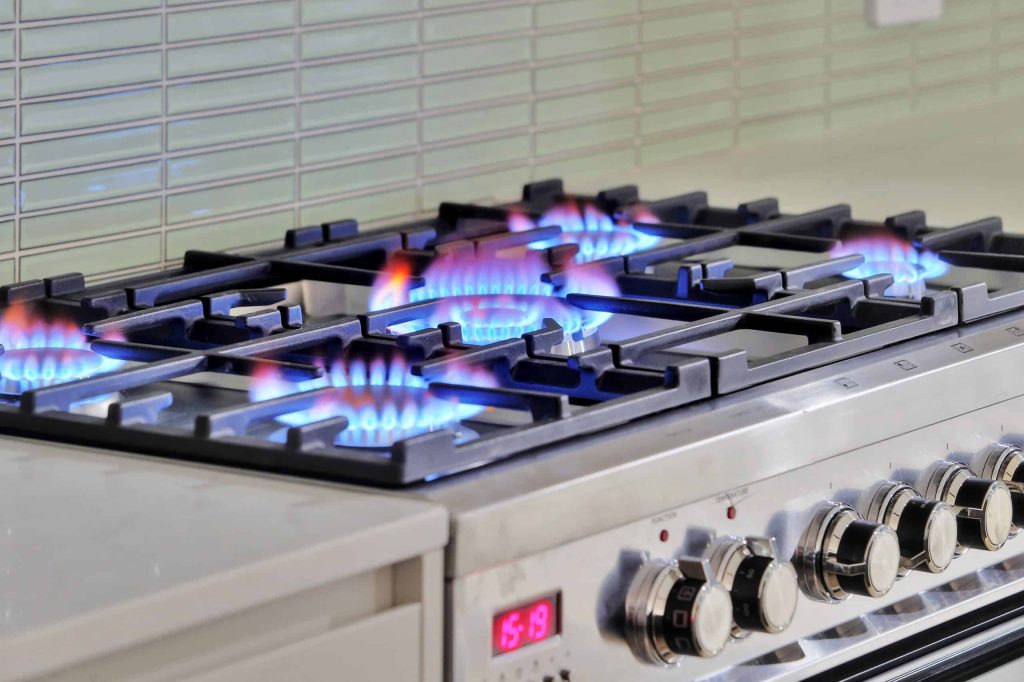 Gas cooktop with lit burners in an Alderley custom home kitchen
