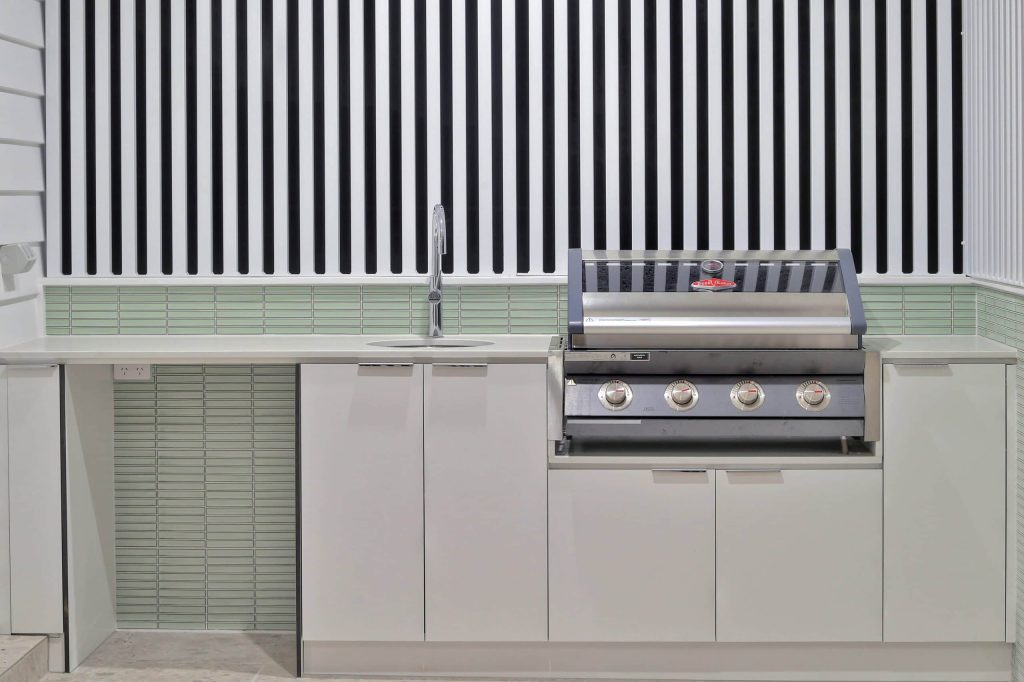 Alfresco kitchen with built-in BBQ, sink and glass tile splashback in an Alderley custom home