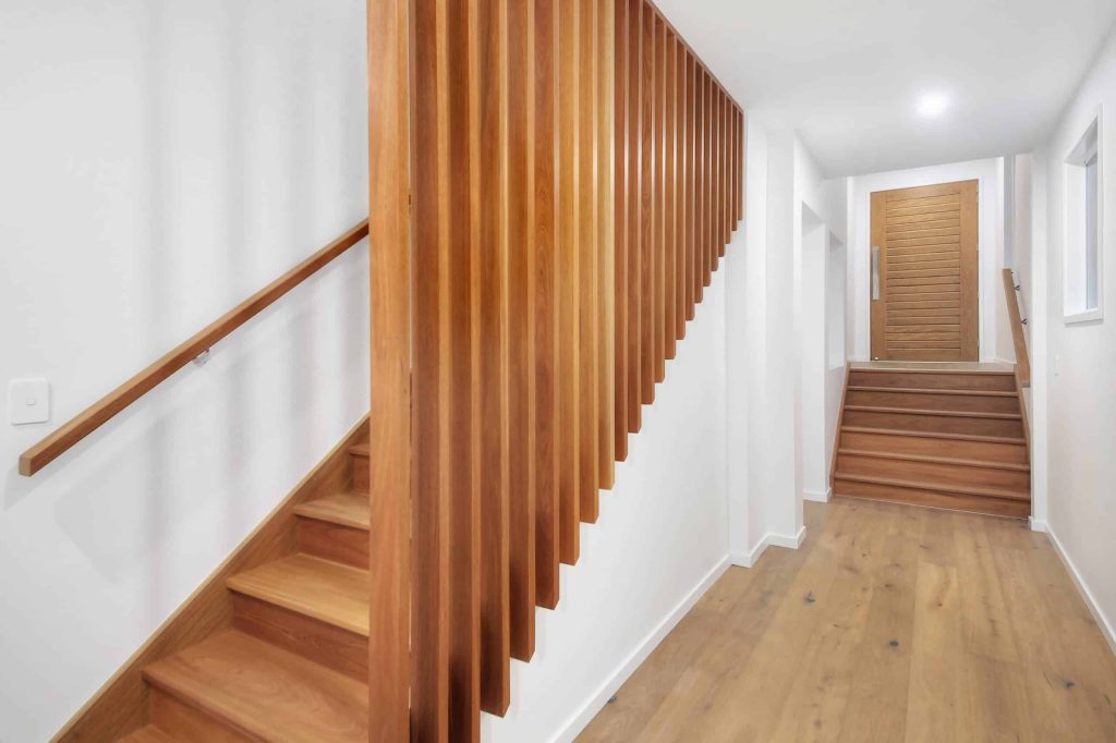 Timber staircase with vertical batten screen and entry hallway in an Alderley custom home