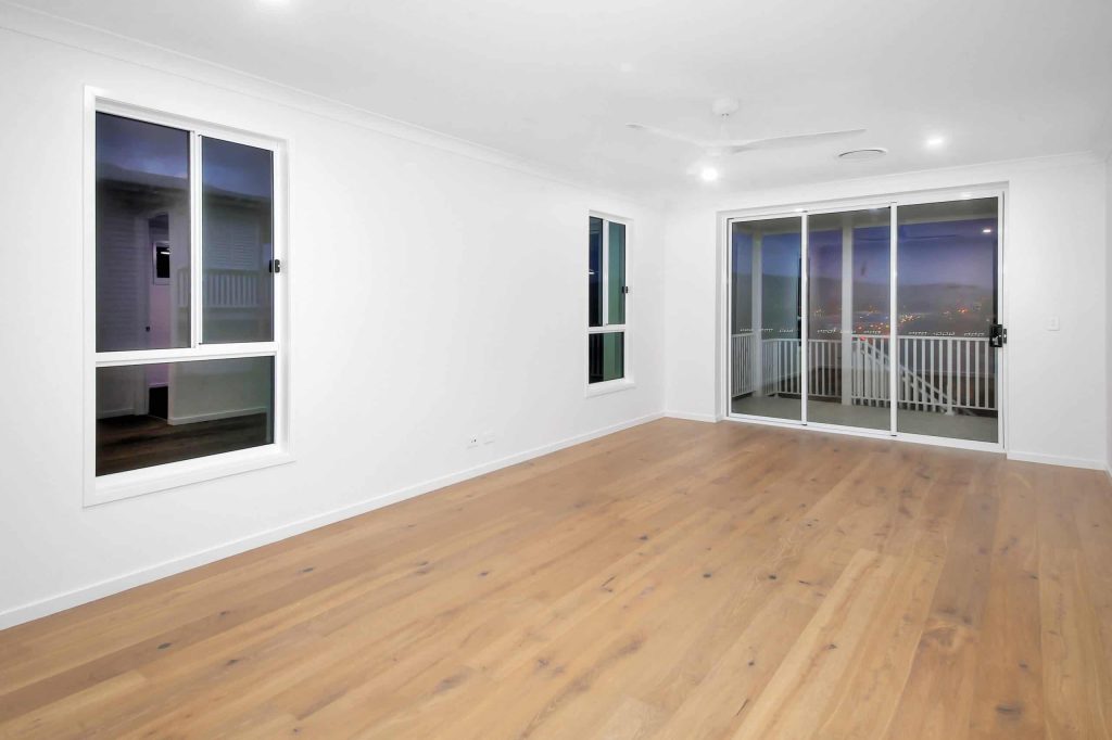 Living room with oak timber flooring and balcony access in an Alderley custom home