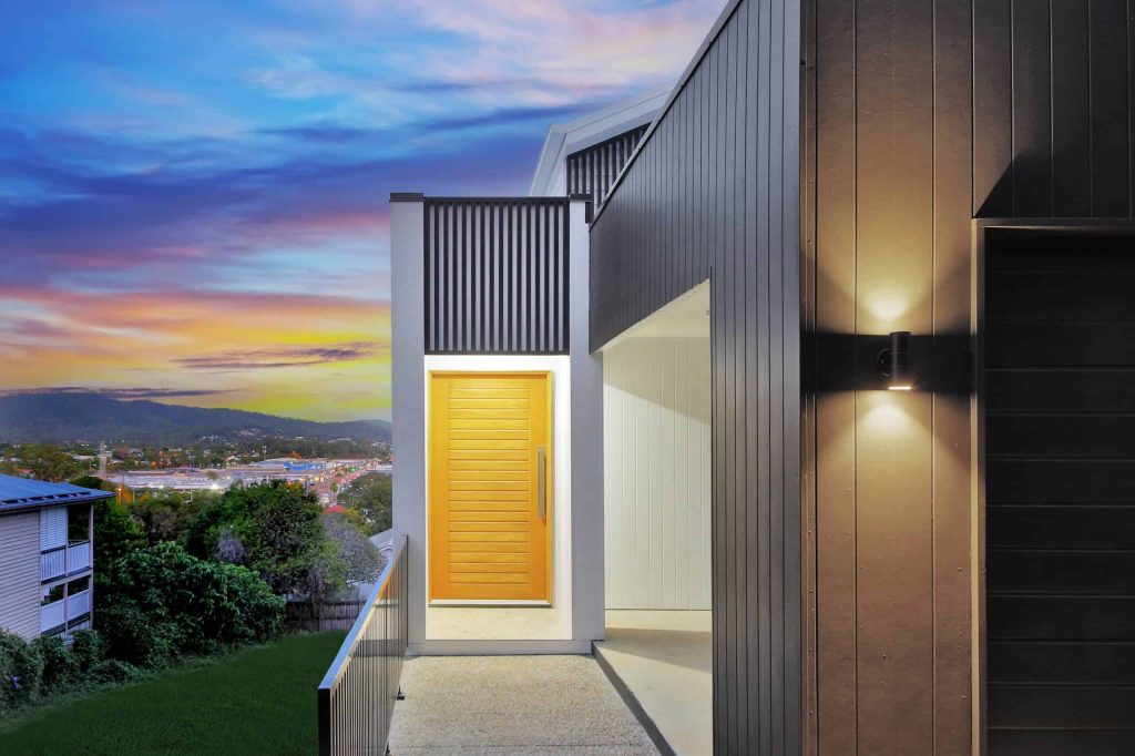 Timber front door entry with dark cladding and hillside views in an Alderley custom home