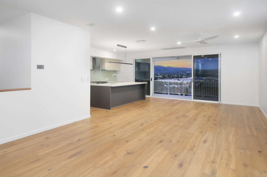 Open plan kitchen and living area with oak flooring and hillside views in an Alderley custom home