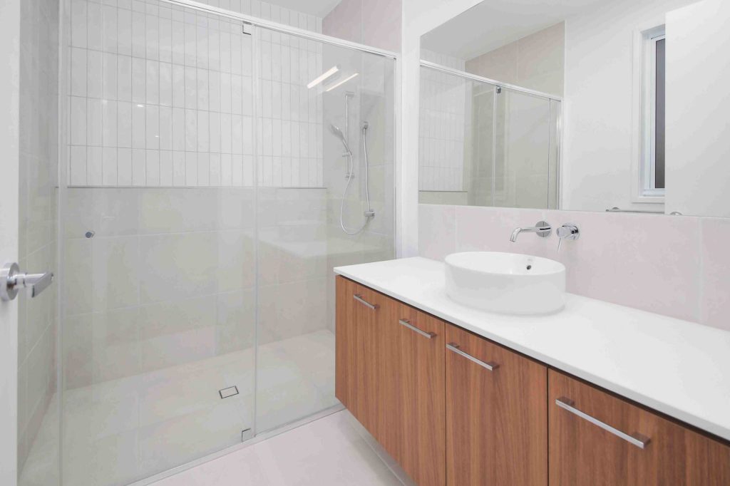 Bathroom with glass shower screen, timber vanity and round basin in a Sunnybank custom home