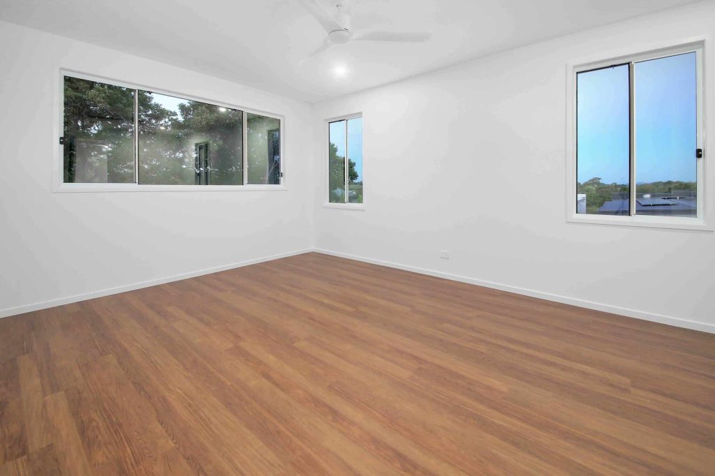 Bedroom with timber flooring, ceiling fan and large windows in a Sunnybank custom home