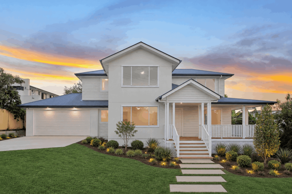 White Hampton style two-storey home with front porch and landscaped gardens at dusk in Sunnybank