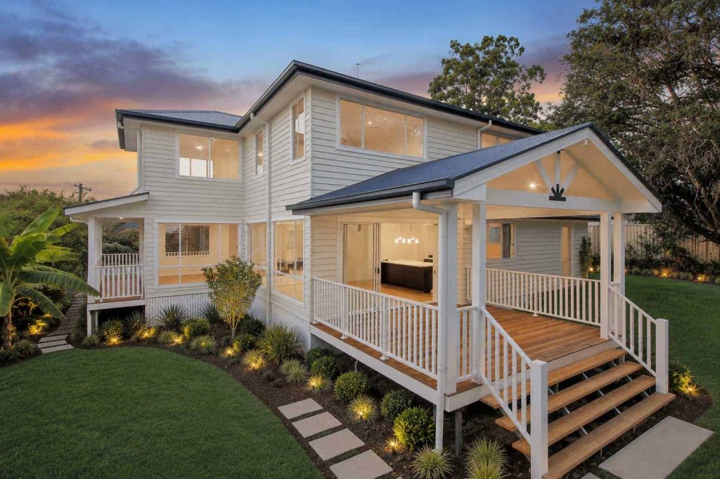 Rear yard of a Hampton style home in Sunnybank with covered timber deck and garden lighting at dusk